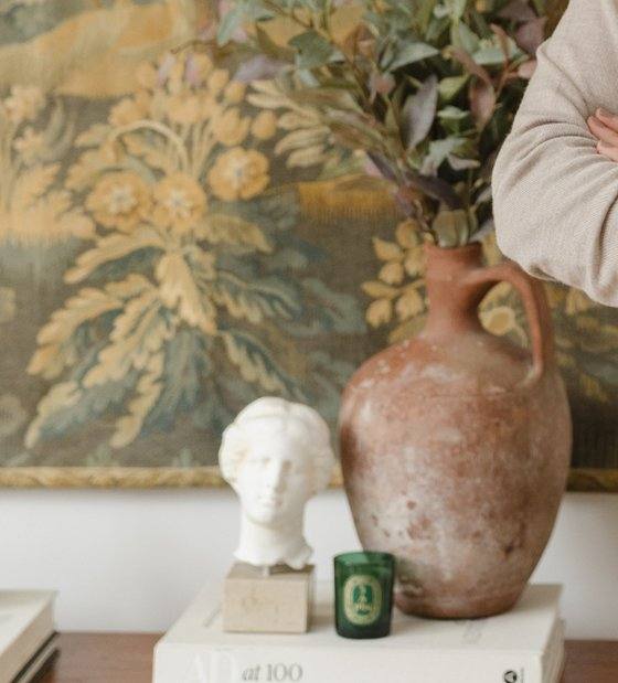 A terracotta vase and marble head against a tapestry