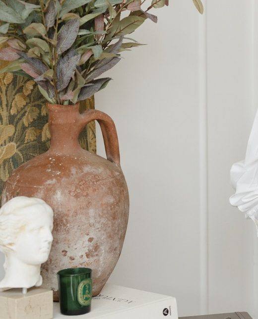 A terracotta vase with eucalyptus beside a marble head